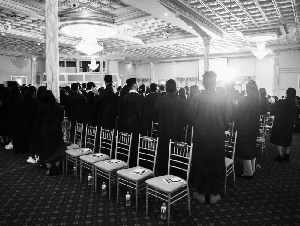 A formal event space with rows of empty chiavari chairs and dramatic lighting.