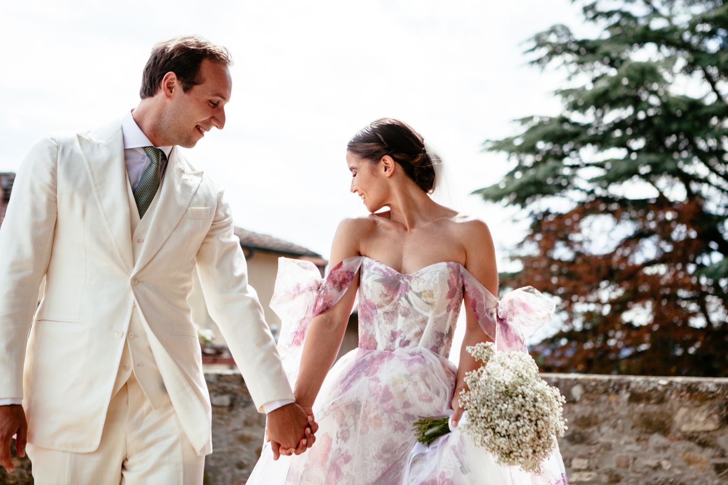 bride and groom hold hands on a warm summer day in Tuscany