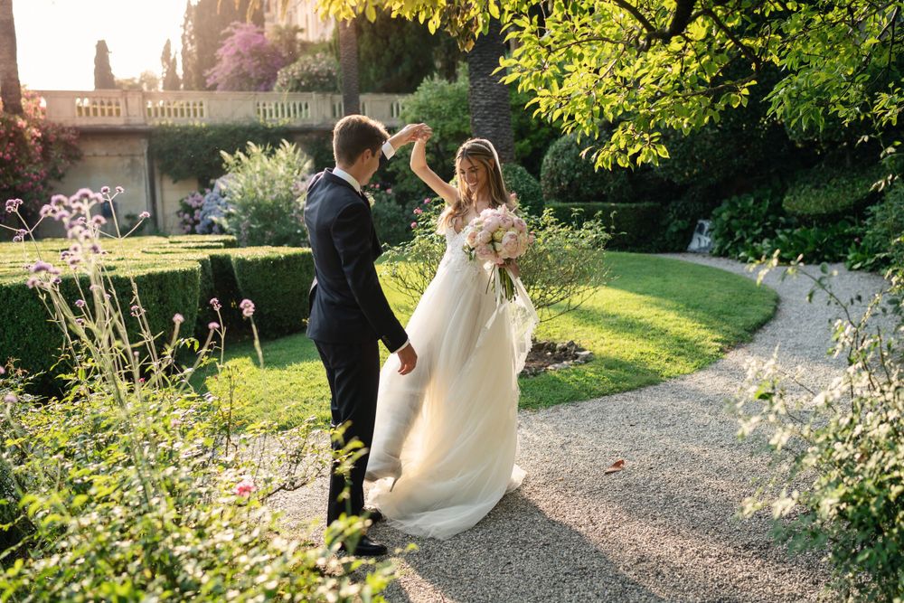 Wedding couple strolls through a lush garden path surrounded by greenery.