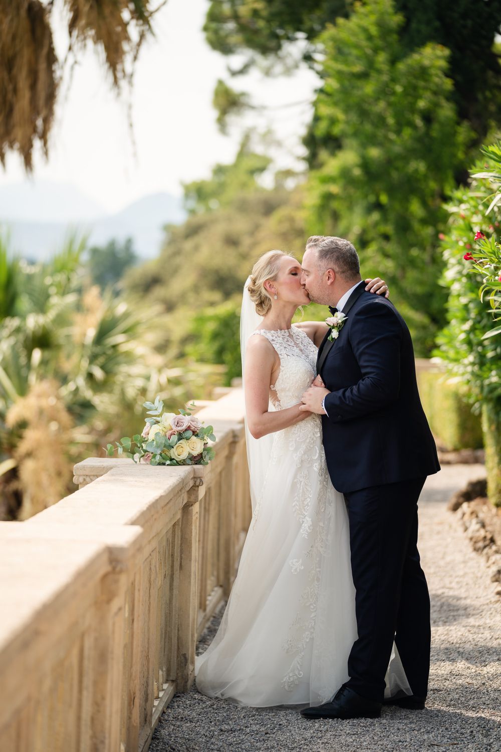 Wedding couple sharing tender moments on a scenic garden pathway.