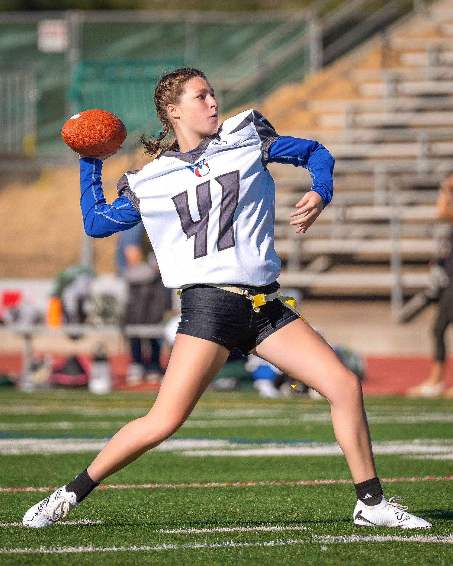 Flag football player throws ball with dynamic form during outdoor game on turf field.