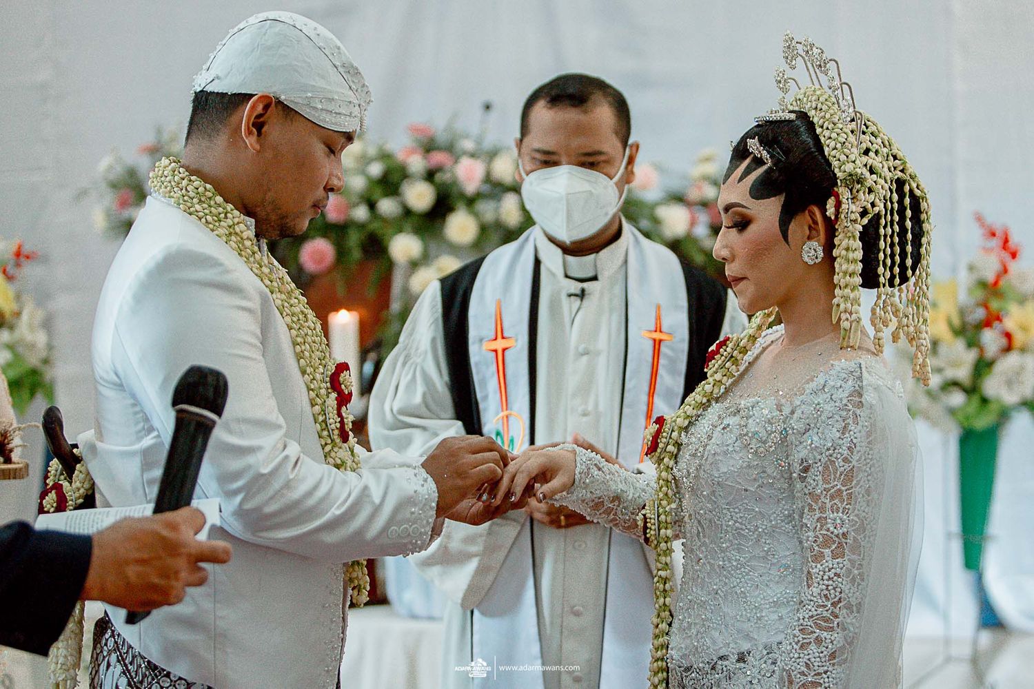 Wedding ceremony with priest and couple exchanging rings during traditional Christian service.