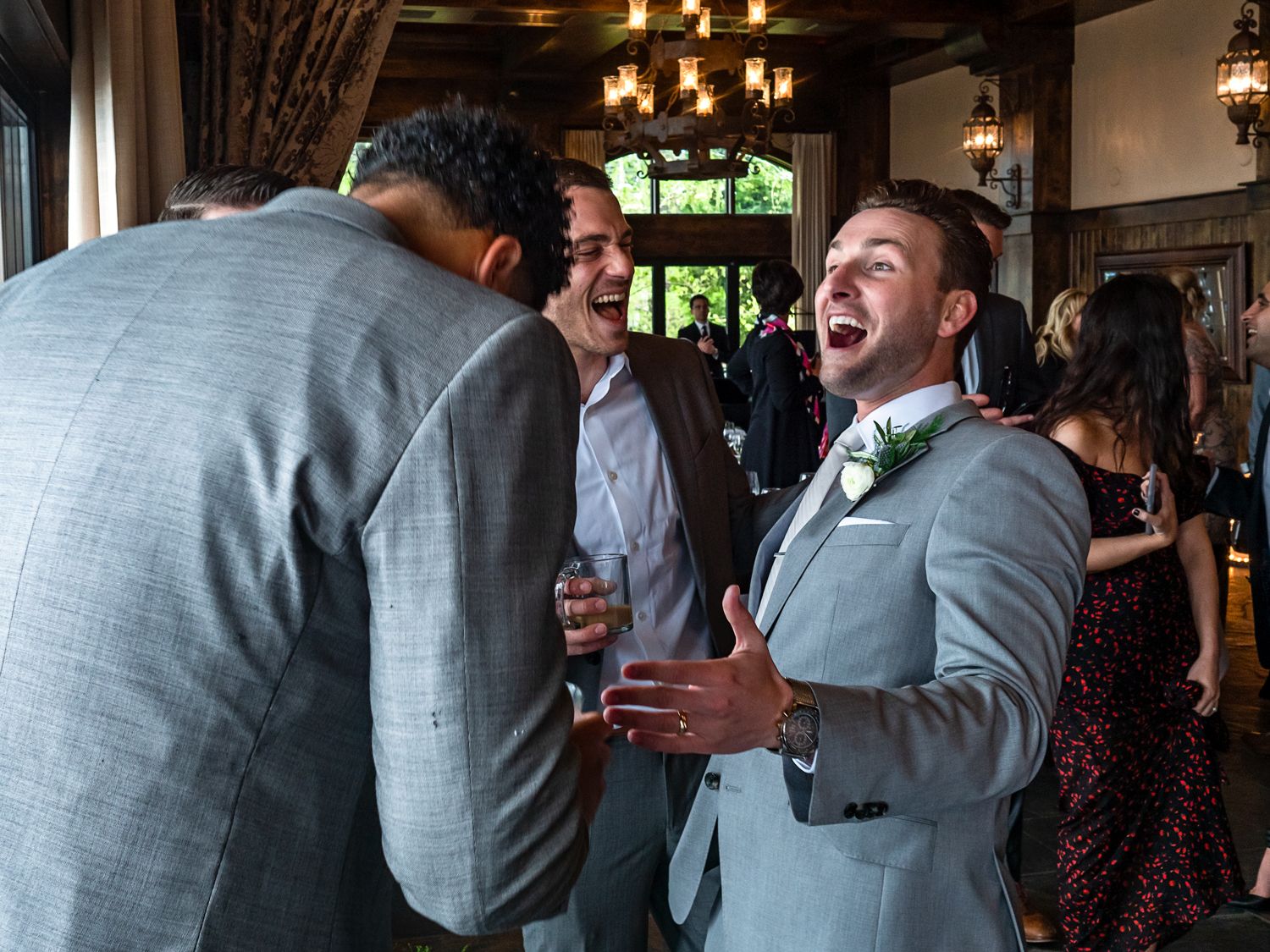 Two people at a formal event share an animated conversation as one person laughs heartily in a gray suit.