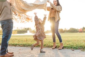 family lifting blanket over little girl