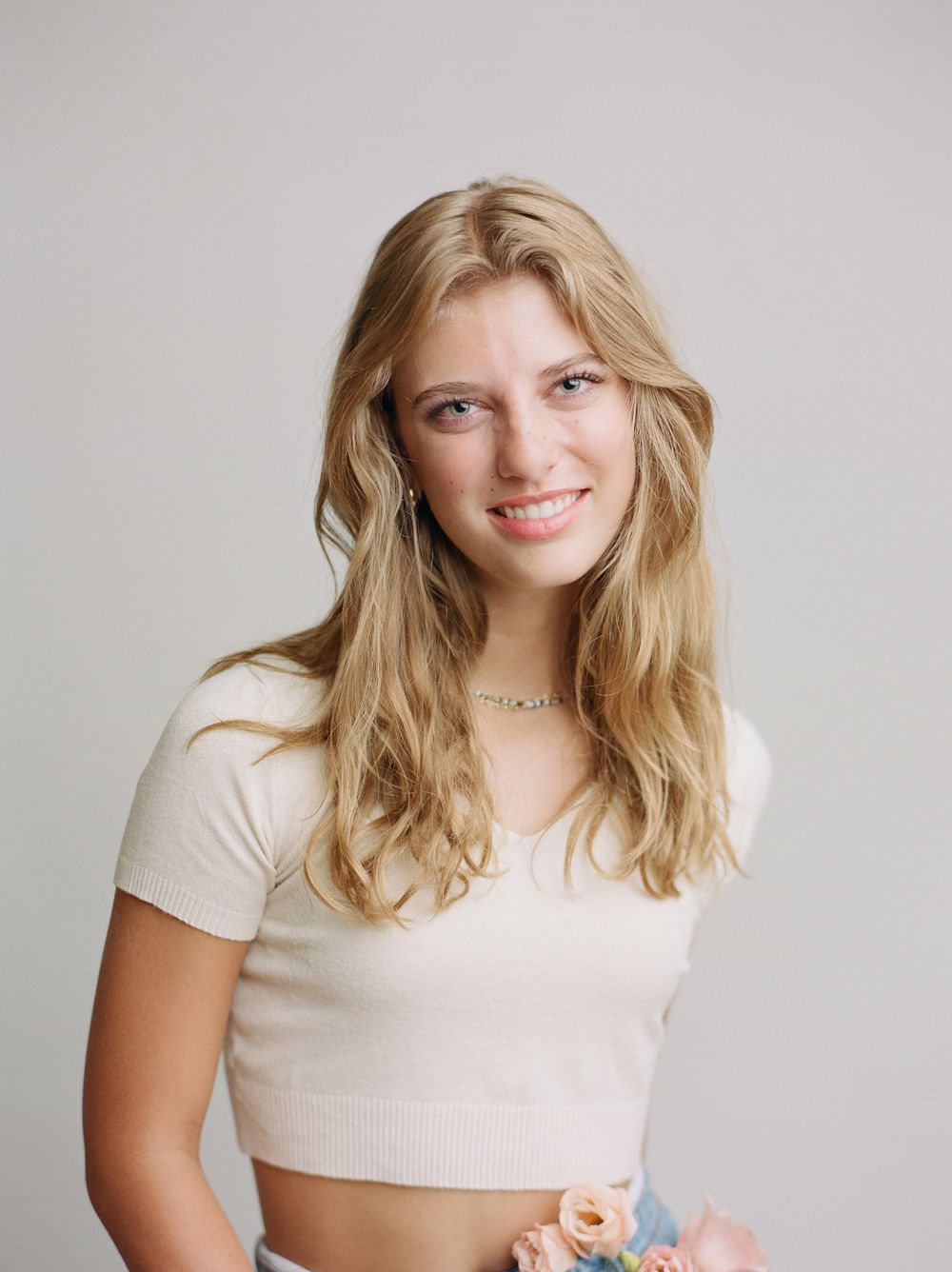 blonde teenager girl wearing ivory cropped sweater against neutral backdrop