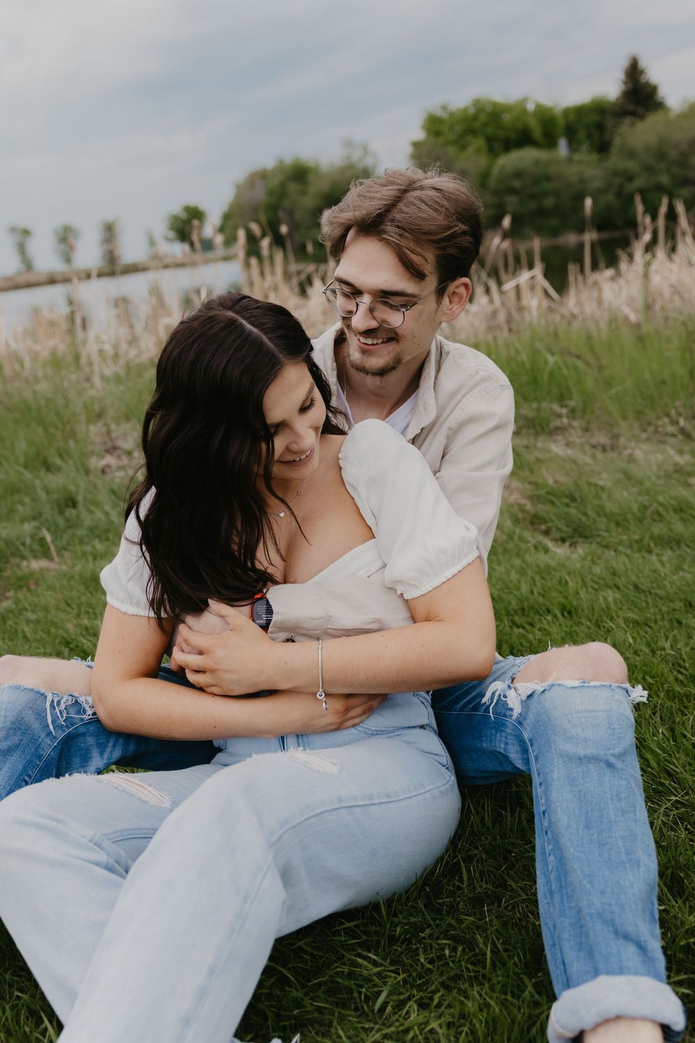 A tender moment between a couple sitting together in a grassy field with natural lighting.