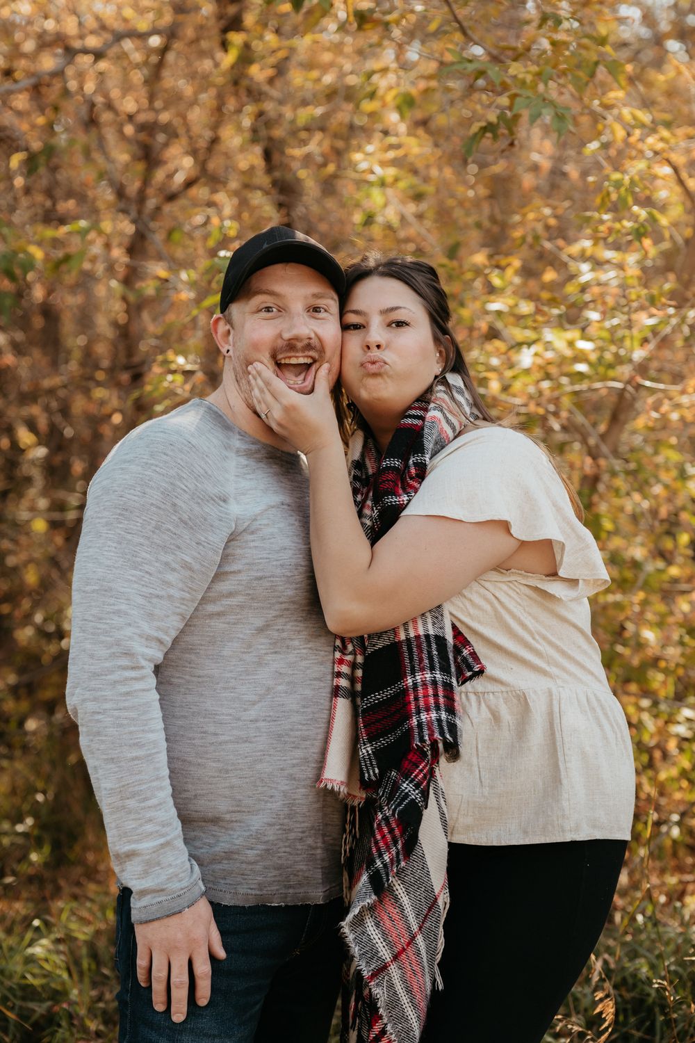Playful couple sharing laughs together in autumn park setting.