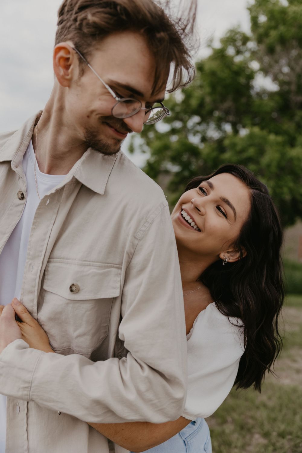 Candid moments of laughter and joy between a couple in casual outdoor portraits.