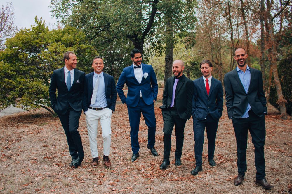 Wedding party in mixed formal attire poses together on autumn grounds.