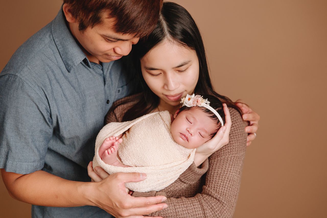 parents holding baby swaddled in wrap