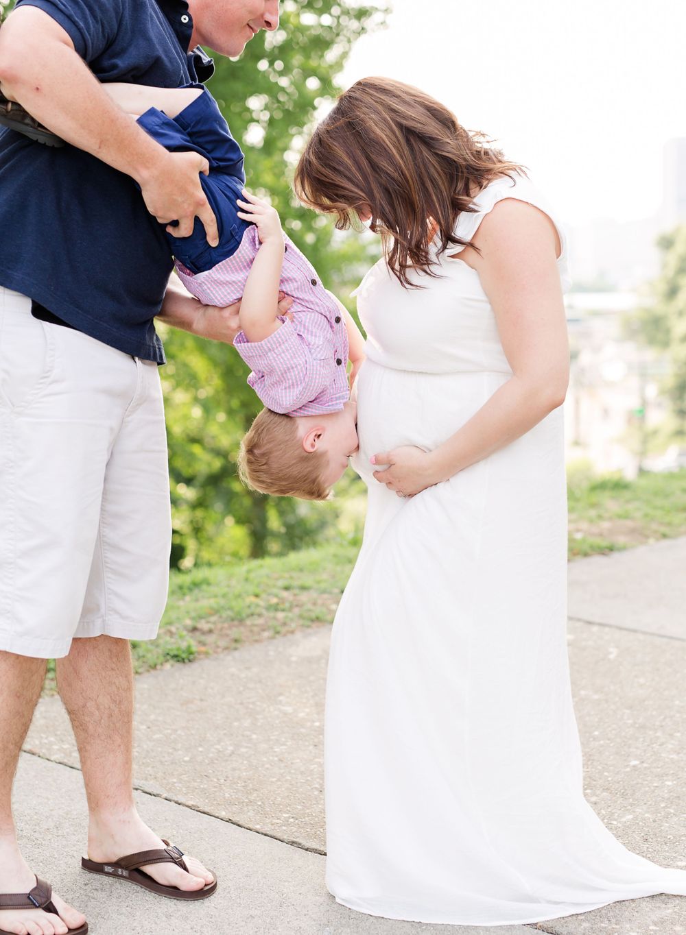 Family plays together during maternity photoshoot outdoors.