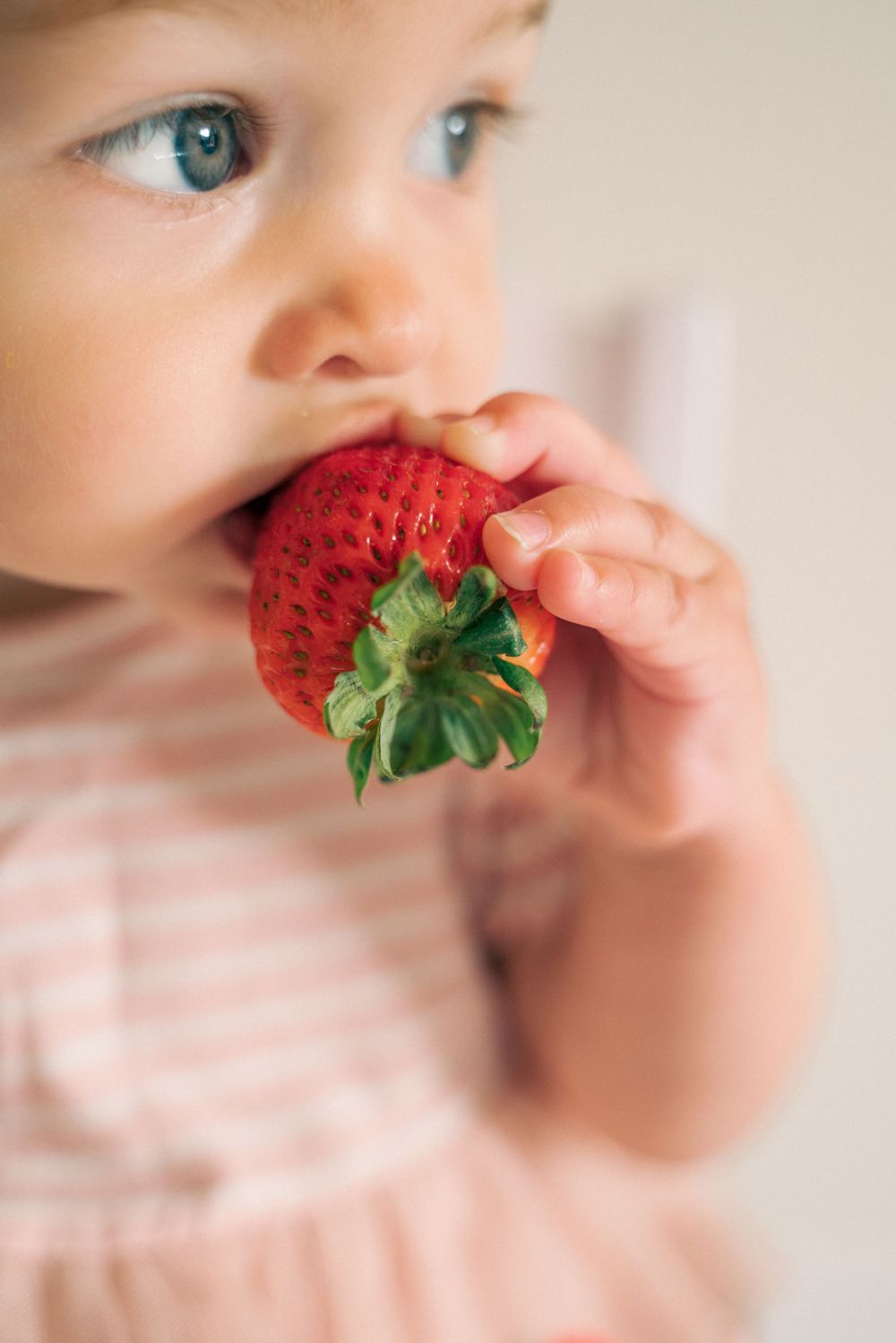 Close-up of a fresh red strawberry being enjoyed against a soft blurred background.
