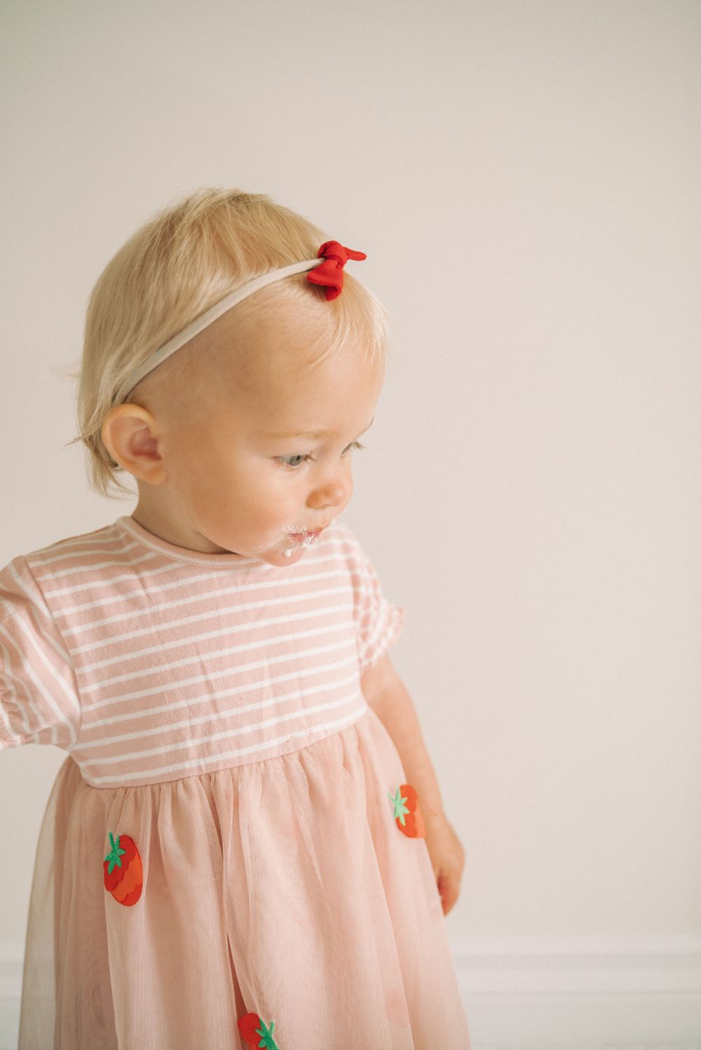 Pink striped dress with strawberry pattern photographed against light wall.