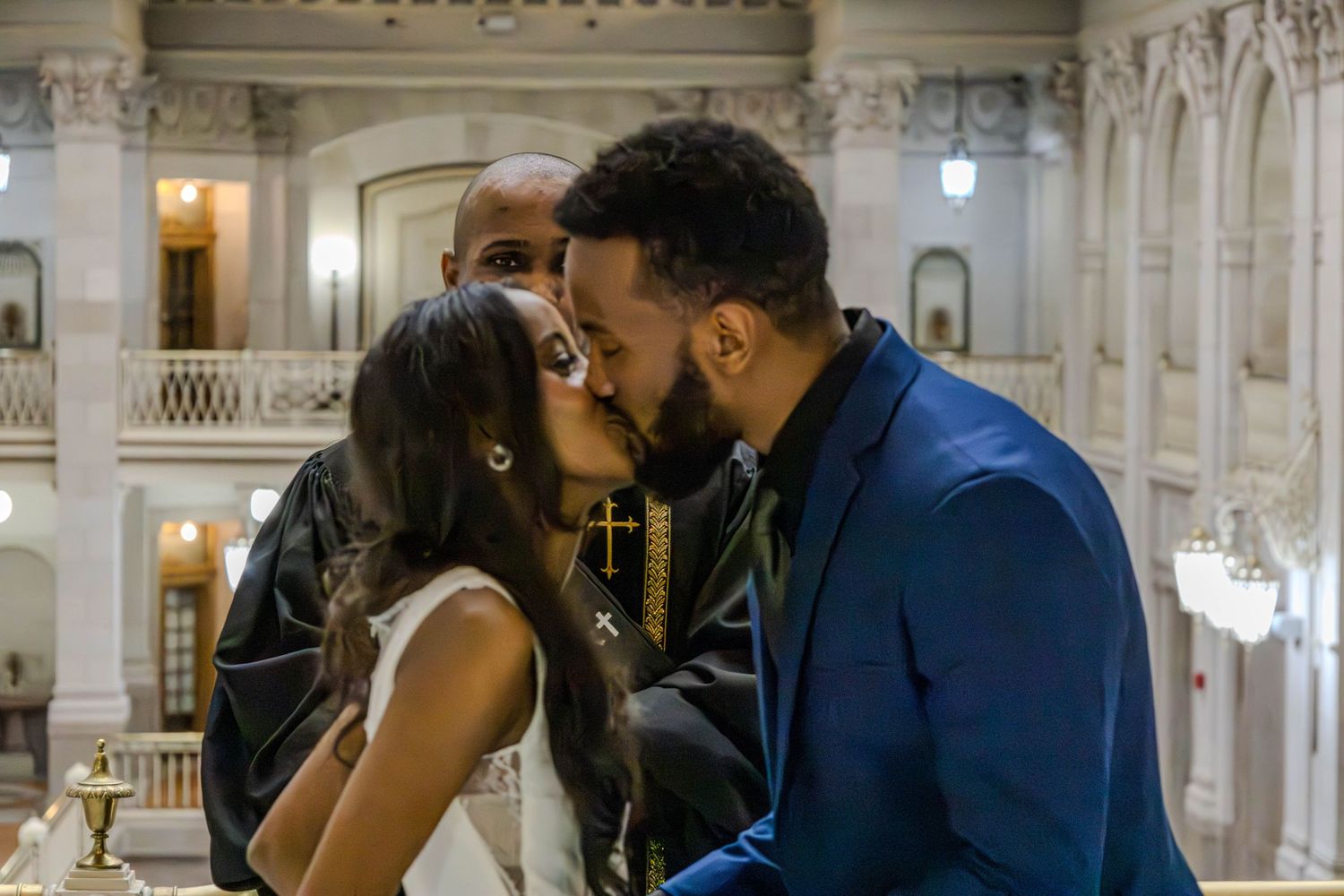 Couple sharing romantic kiss in ornate historic building with elegant architecture.