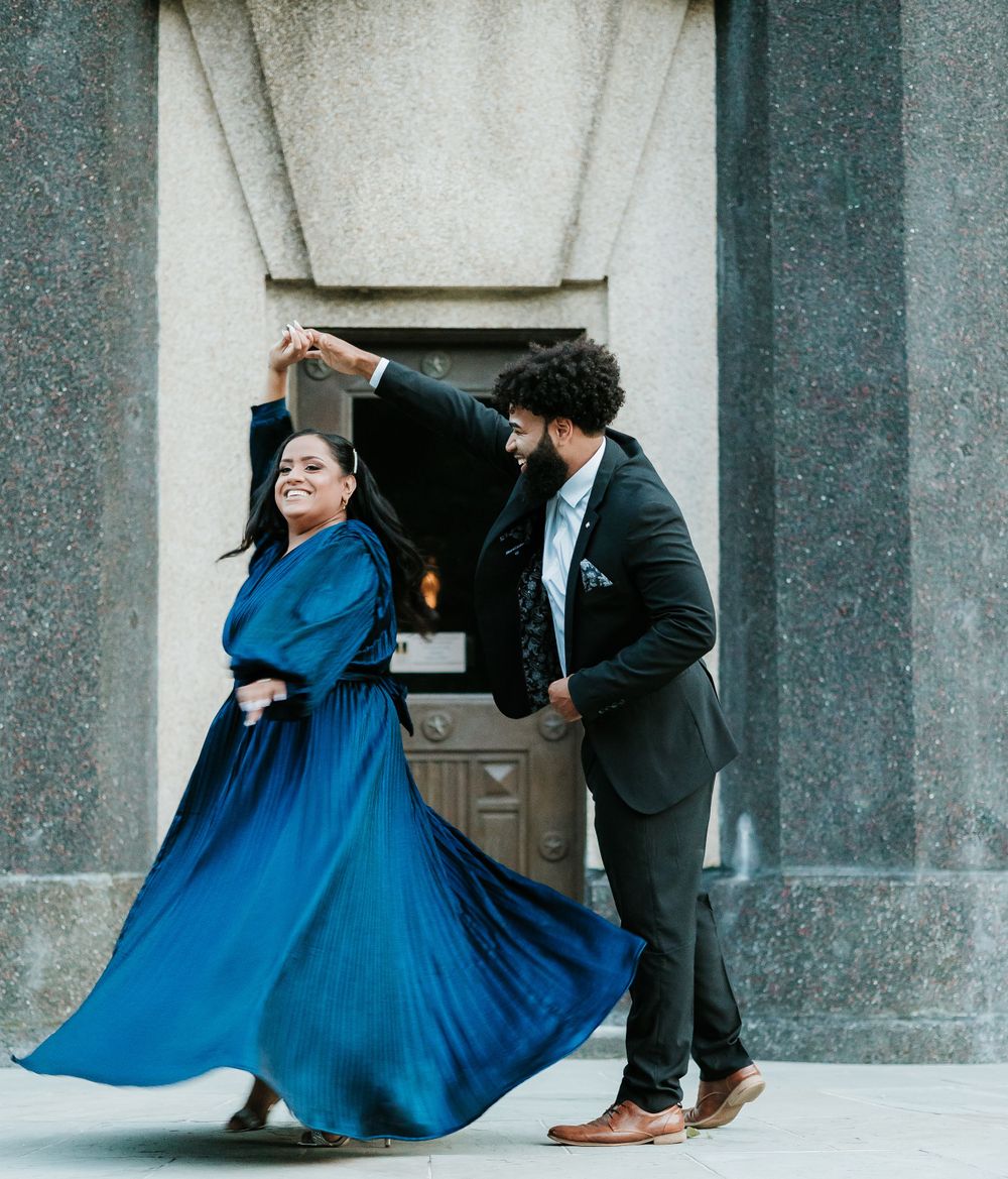 Couple dancing together in an elegant pose against a stone architectural backdrop.
