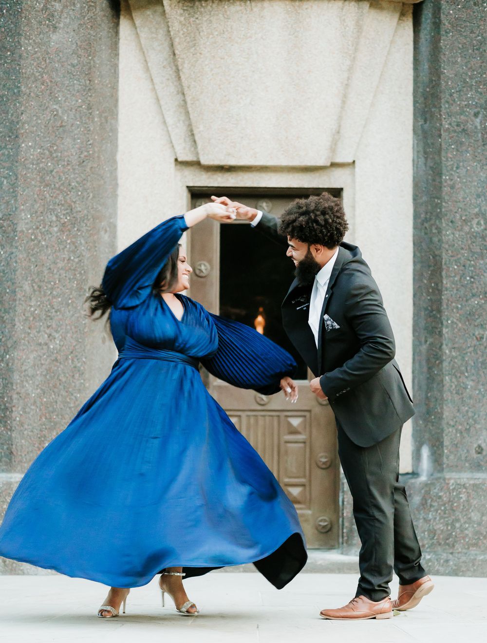 A couple dancing together with the woman wearing a flowing royal blue dress and twirling gracefully.