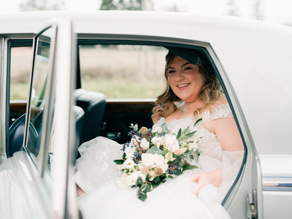 White classic car decorated for wedding with bride seated inside.