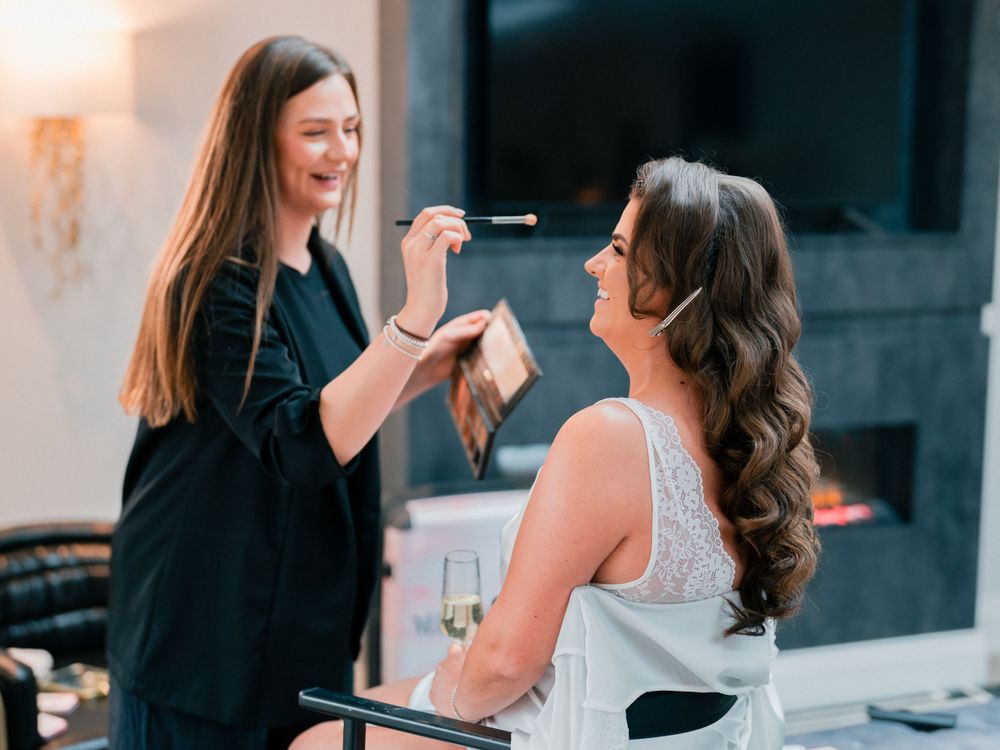 Makeup artist applies cosmetics to bride during wedding day preparations.