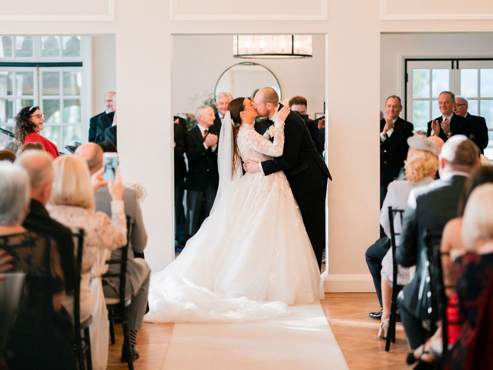 Wedding reception guests dancing and celebrating in bright indoor venue.