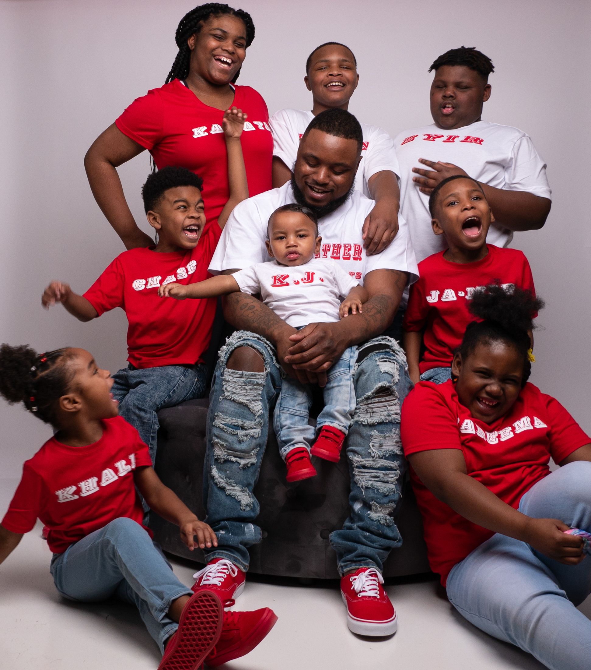 Group wearing matching red and white t-shirts posing together for a casual studio portrait.
