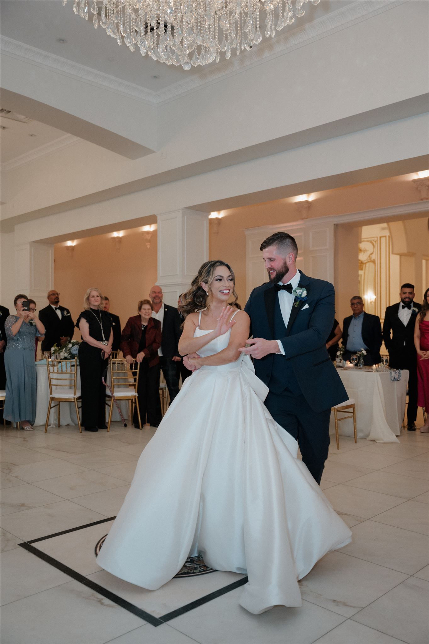 A joyful moment during the wedding dance under sparkling chandeliers.