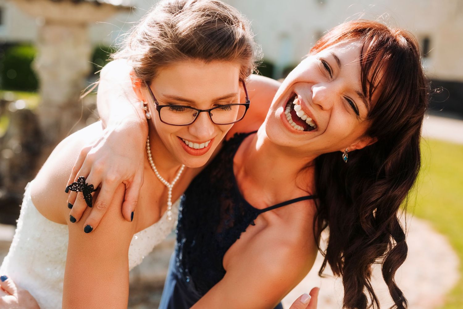 Two friends sharing genuine laughter during sunny outdoor moment.