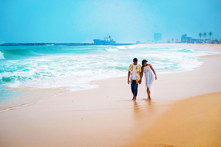 A couple, man and wife hold hands as they walk down the beach