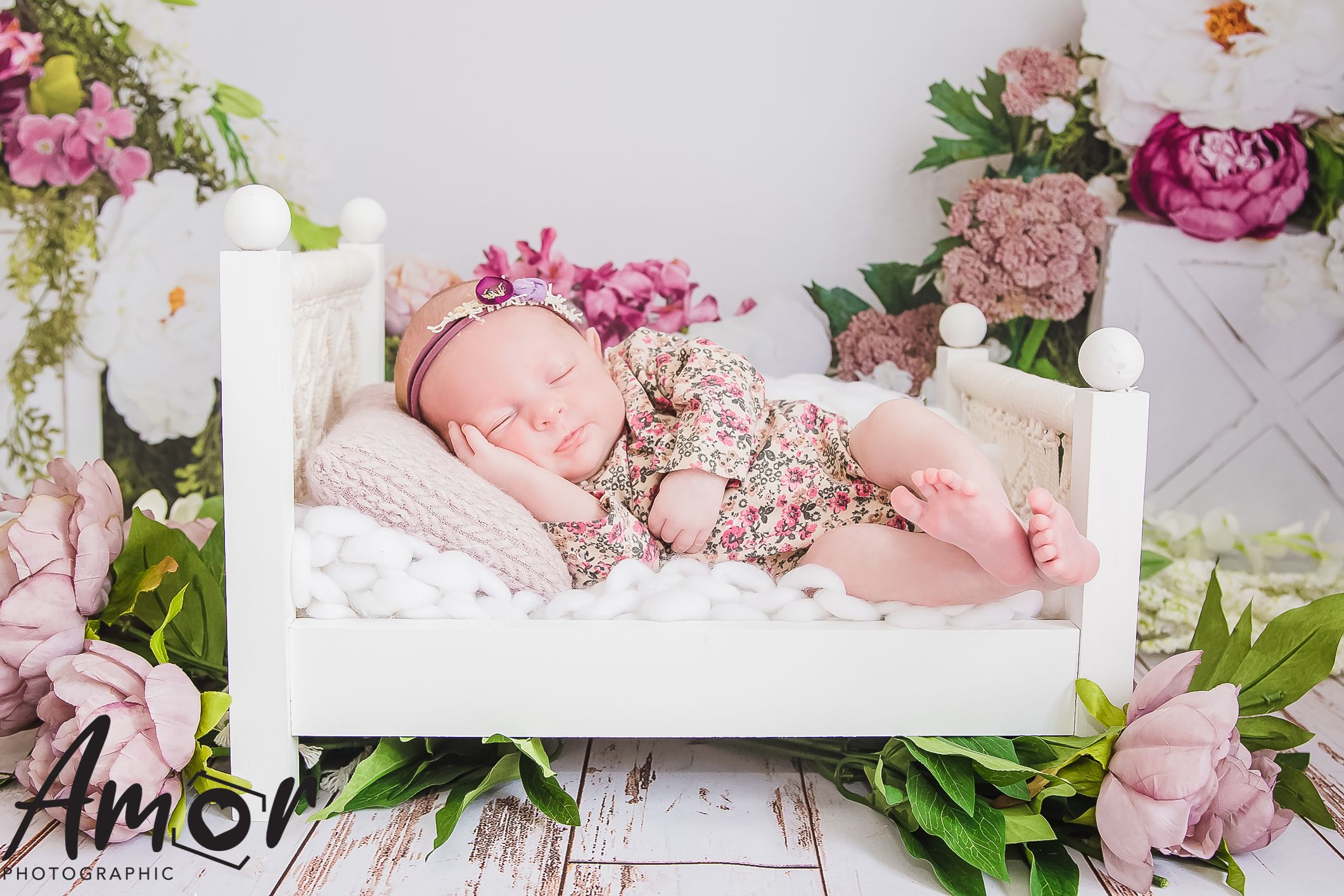 Delicate floral nursery scene with white bed and pink roses.