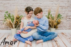Family portrait against brick wall with dried pampas grass decorations.