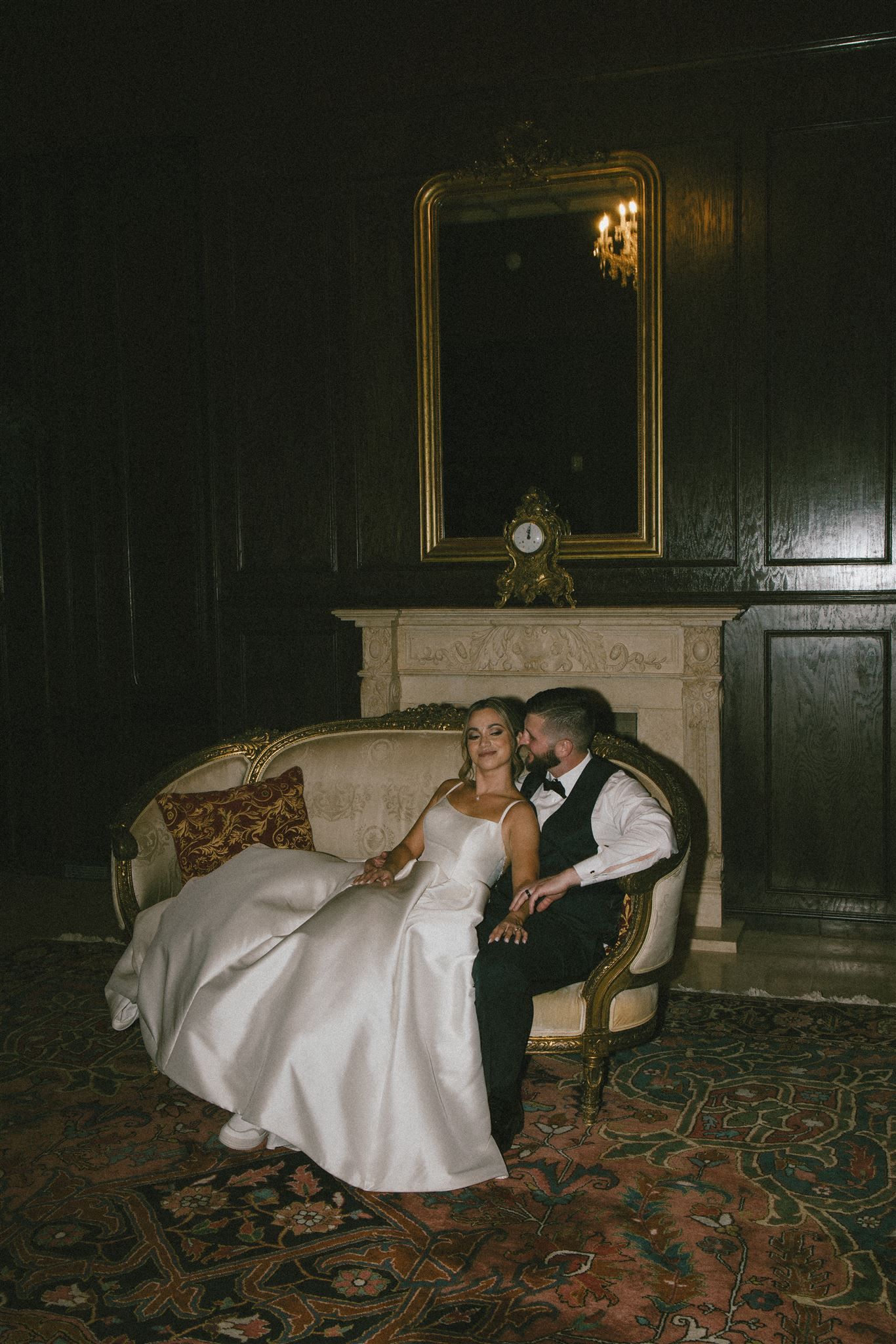 Intimate moment captured in vintage setting with antique mirror and fireplace.