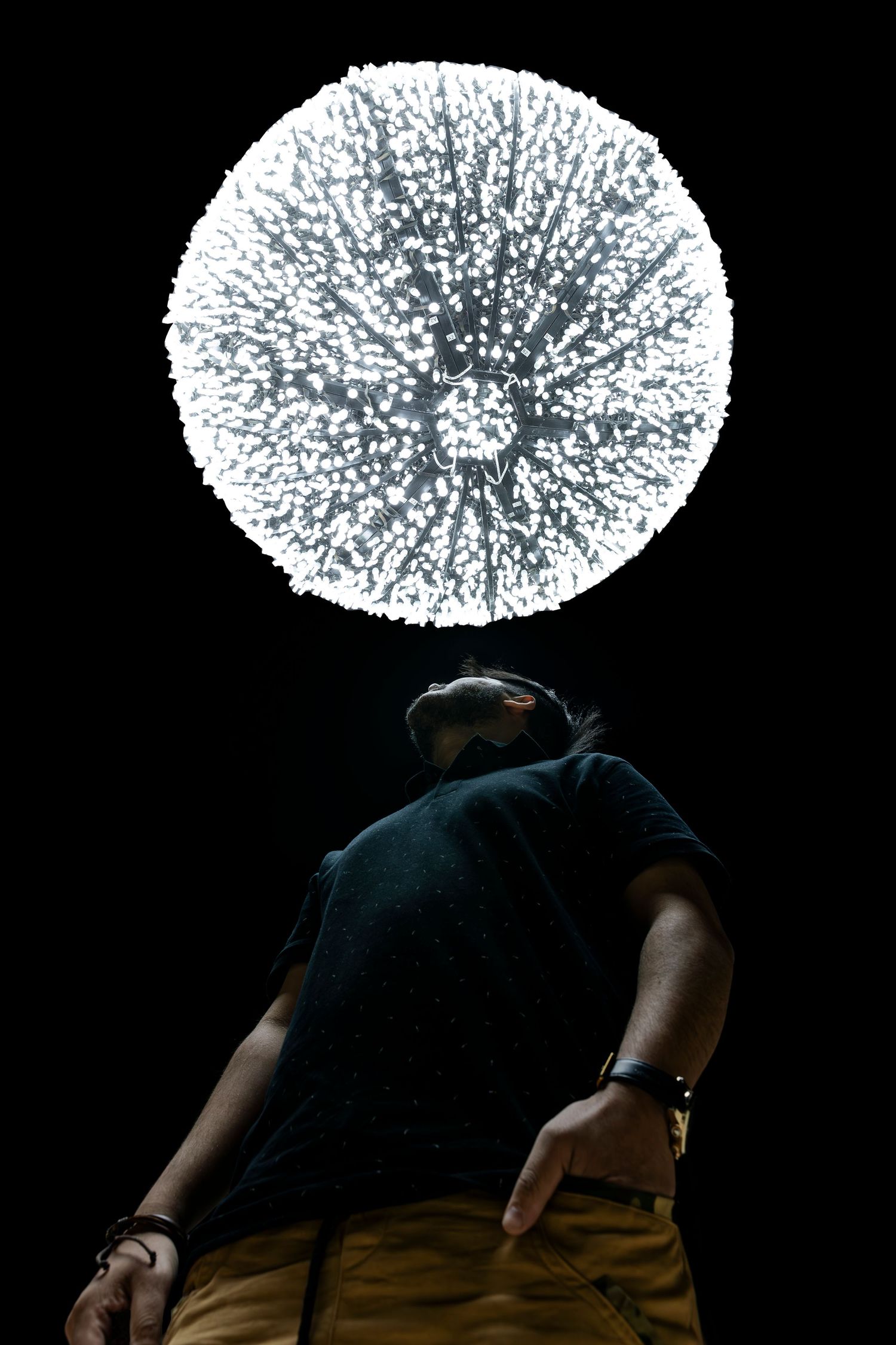 Glowing white spherical light installation against dark background creates dramatic silhouette.