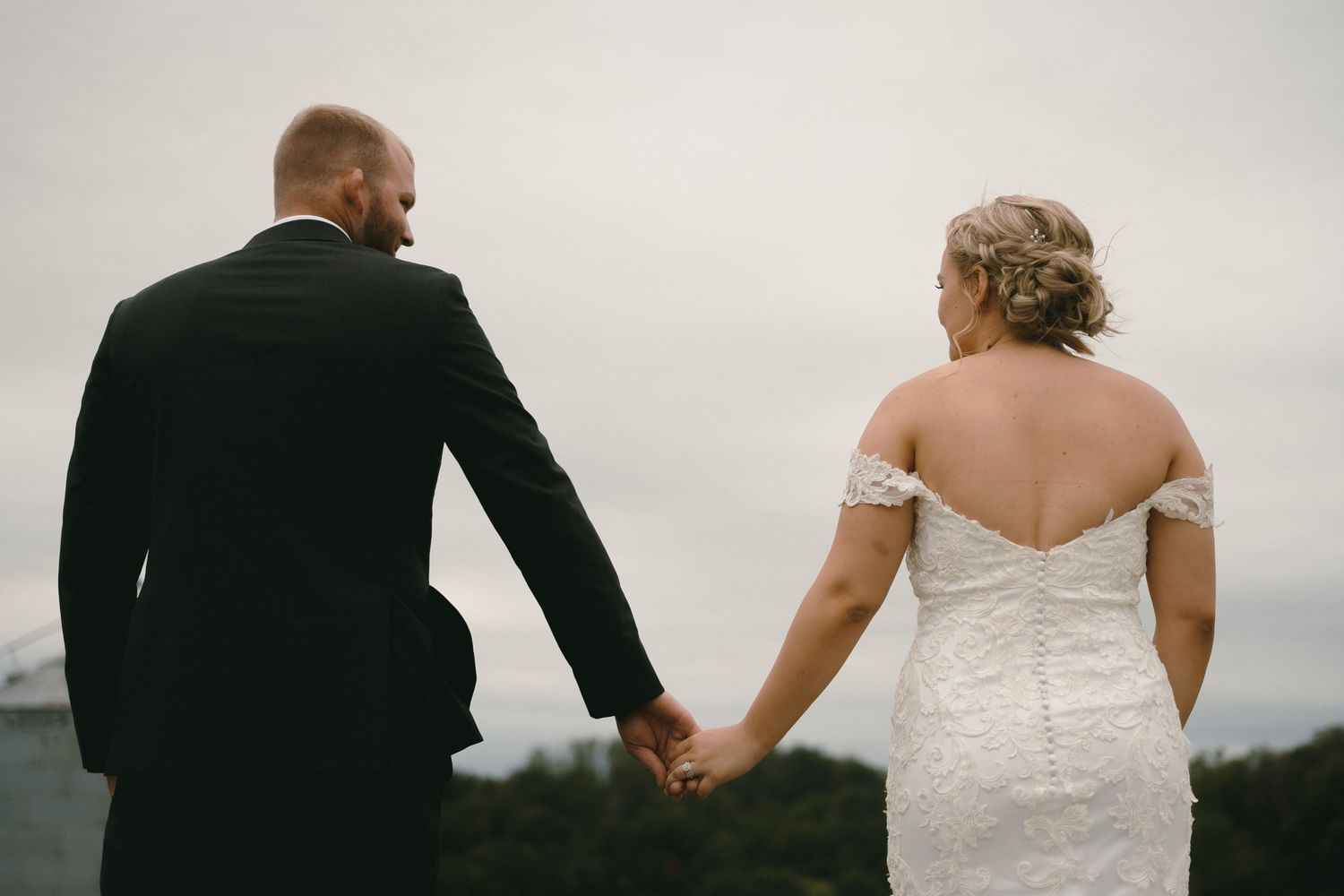 A wedding couple walks together outdoors in formal attire.