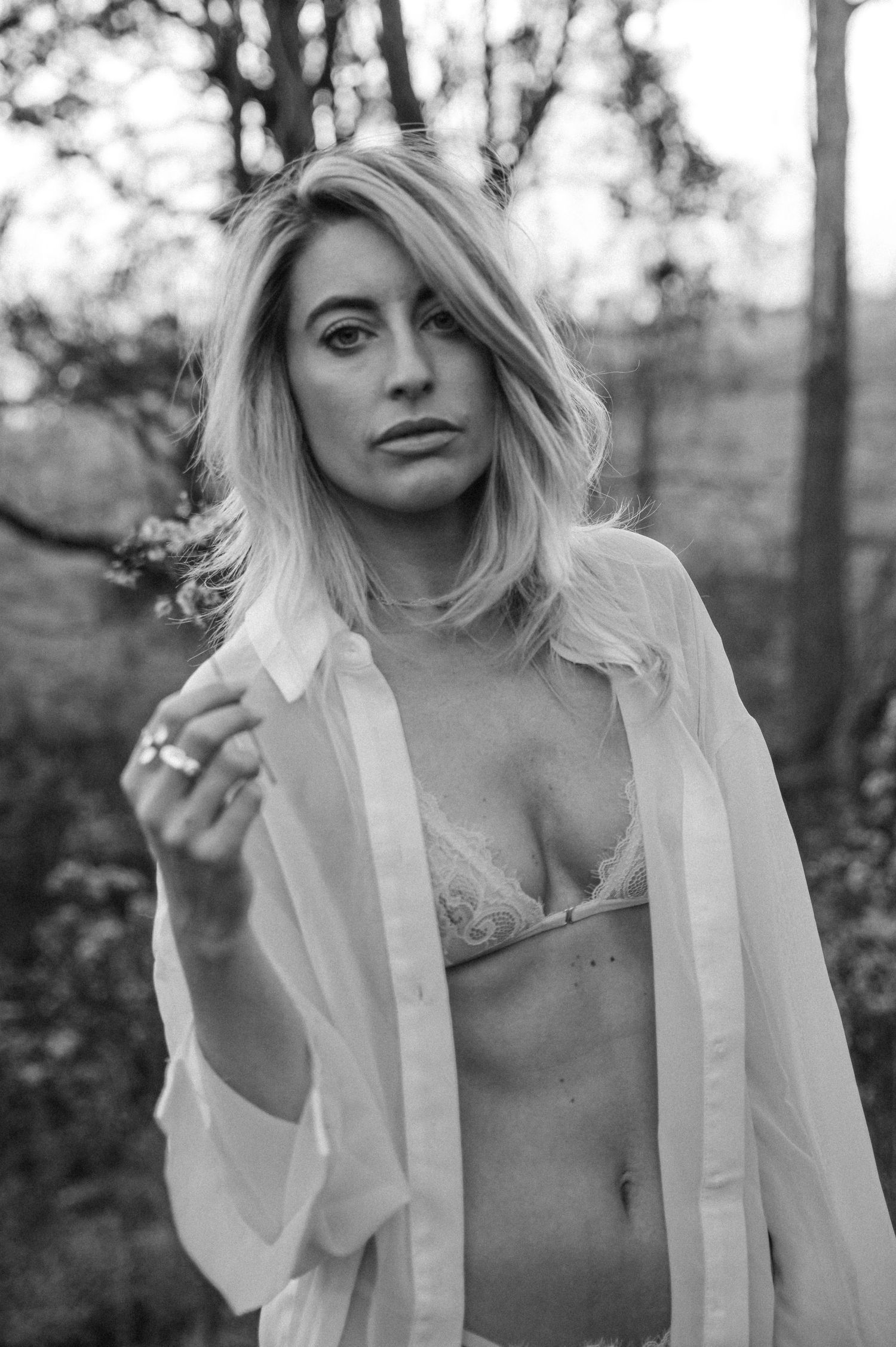 Black and white artistic portrait series showing a person in a white button-up shirt against a natural outdoor background.