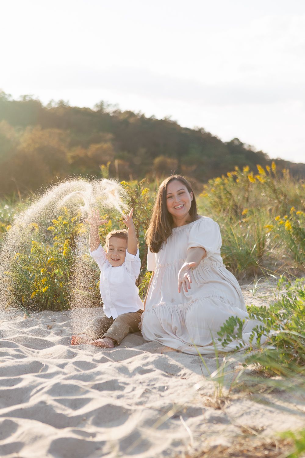 a candid moment of mom and toddler son sitting and playing with sad with beautiful light by Paula Ortiz NY Family Photos