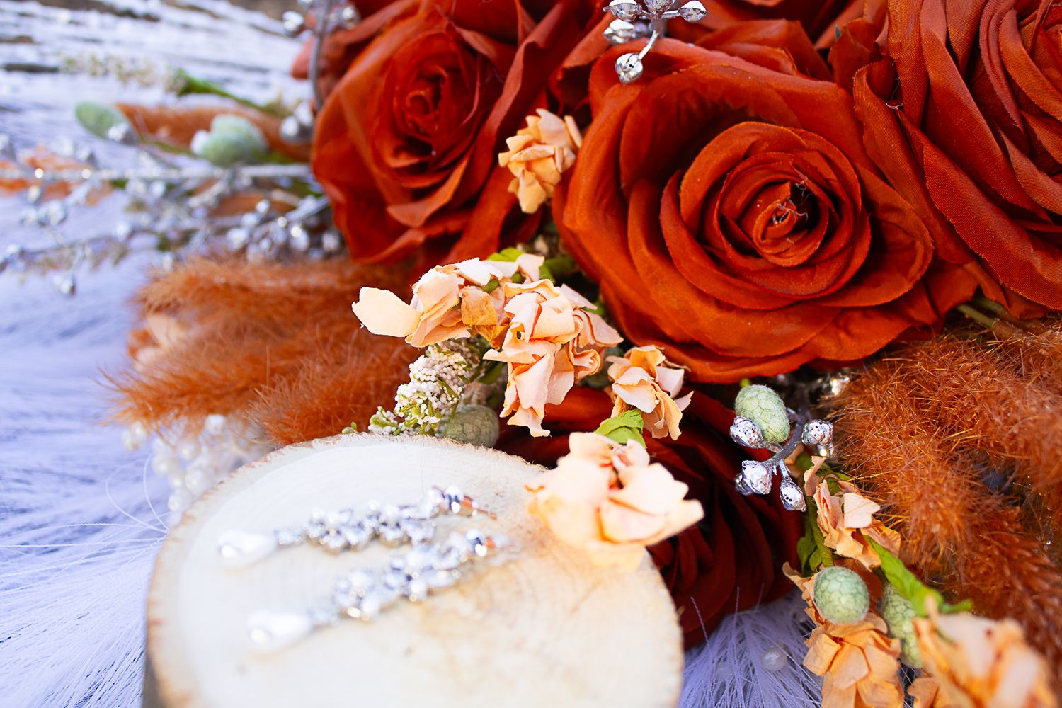 Close-up of orange roses and delicate floral wedding decorations.