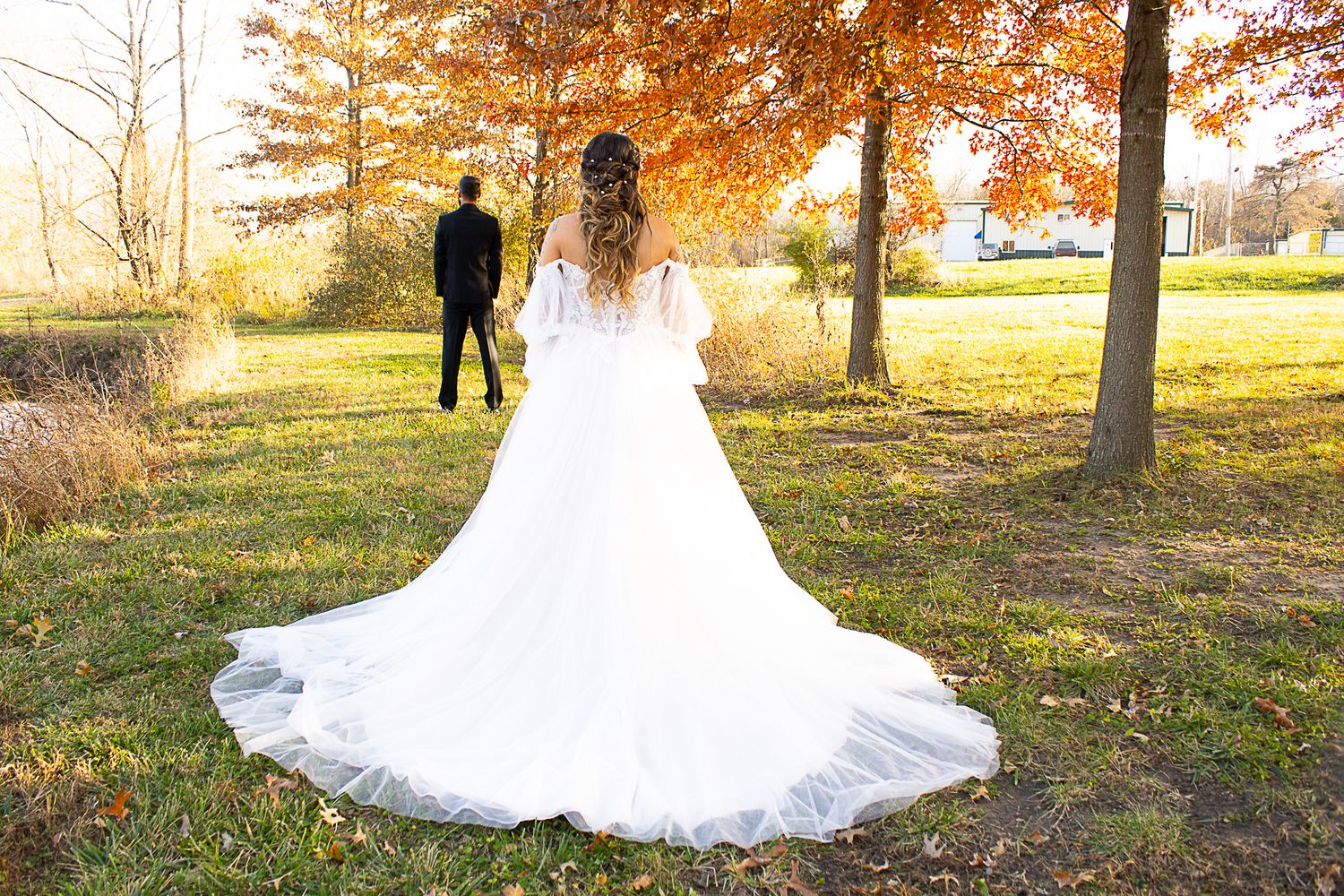 A bride in a flowing white dress with long train photographed in an autumn setting.