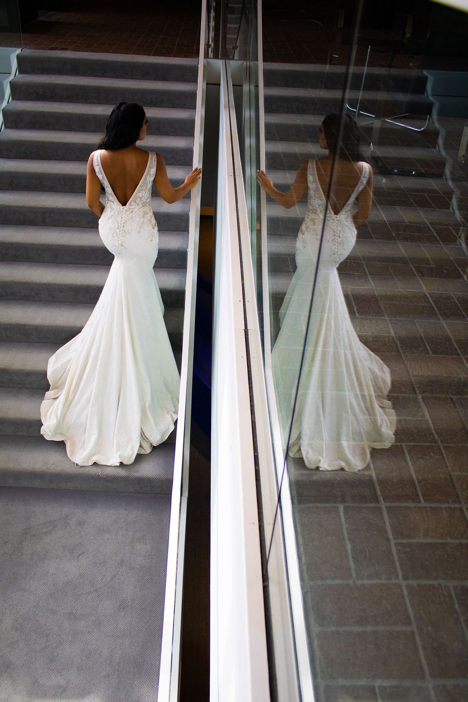 Reflective series showing white formal dress in modern mirror hallway.