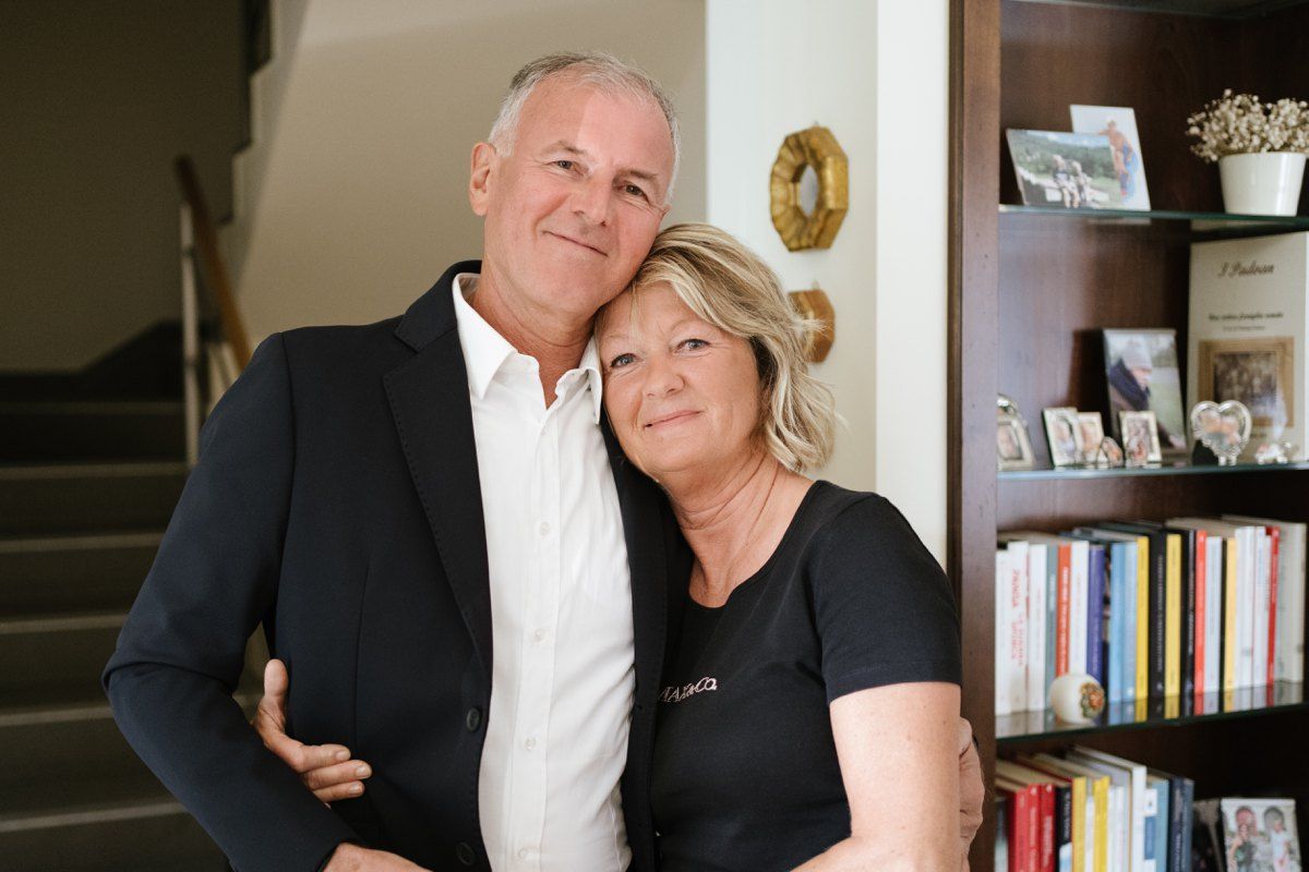 Couple in casual formal wear embracing in front of bookshelf at home.