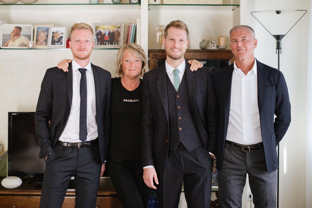 Family group photo in living room with four people in formal attire.