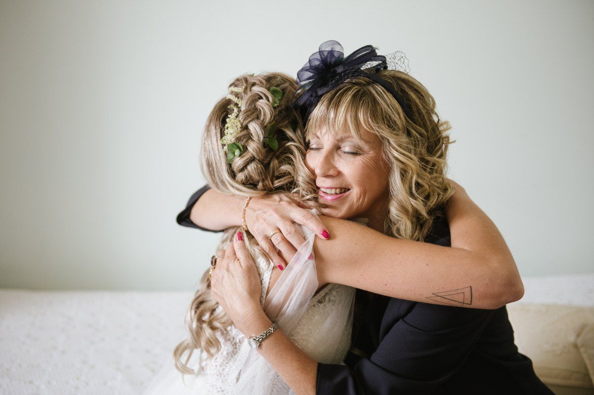 Two women share an emotional embrace during wedding preparations.