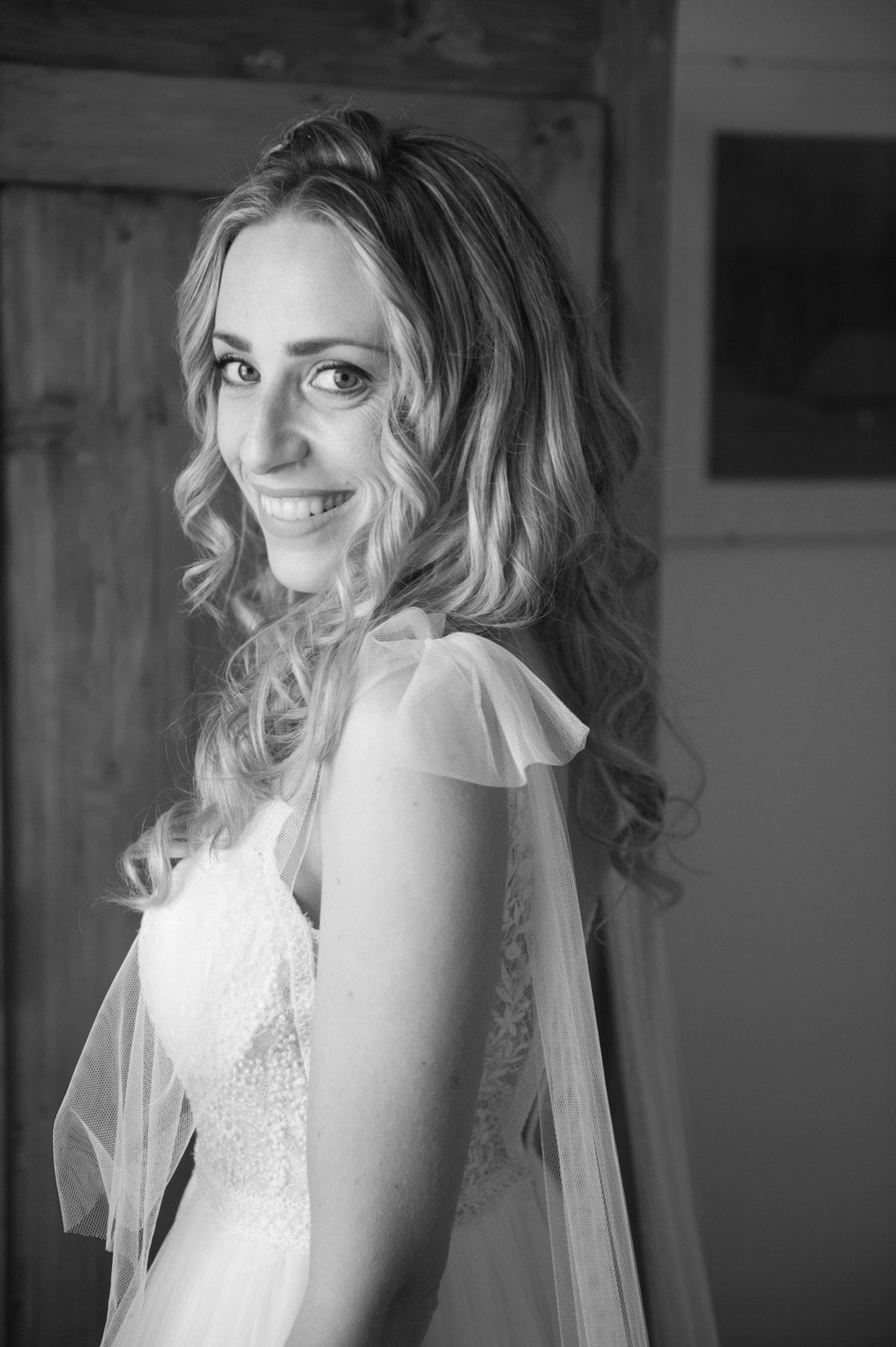 Black and white portrait of bride in lace wedding dress with flowing veil.