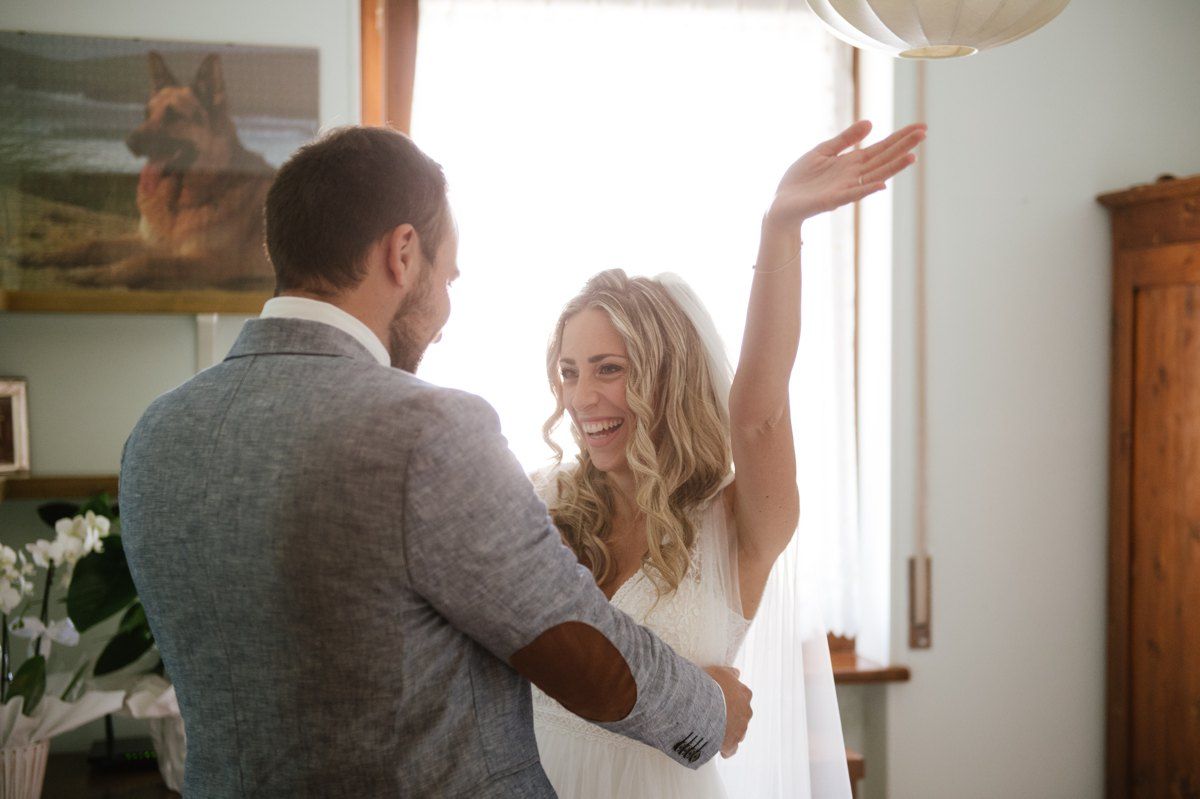 Newlyweds dance together in a sunlit room with rustic wooden decor.