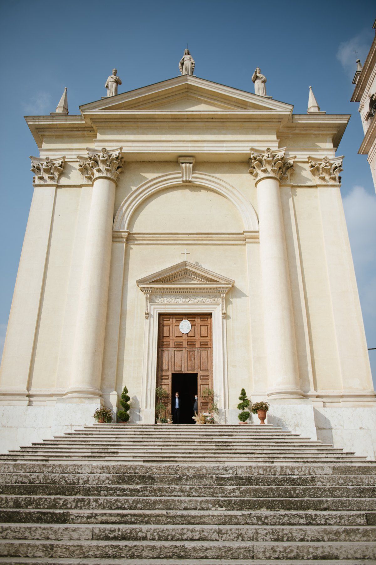 Grand neoclassical church facade with white columns and stone steps leading to wooden doors.