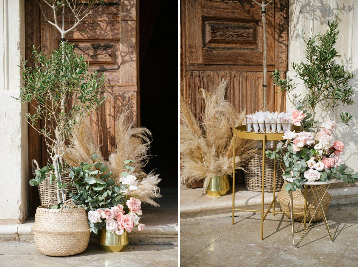 Elegant wedding decor featuring potted greenery and pampas grass against rustic wooden doors.