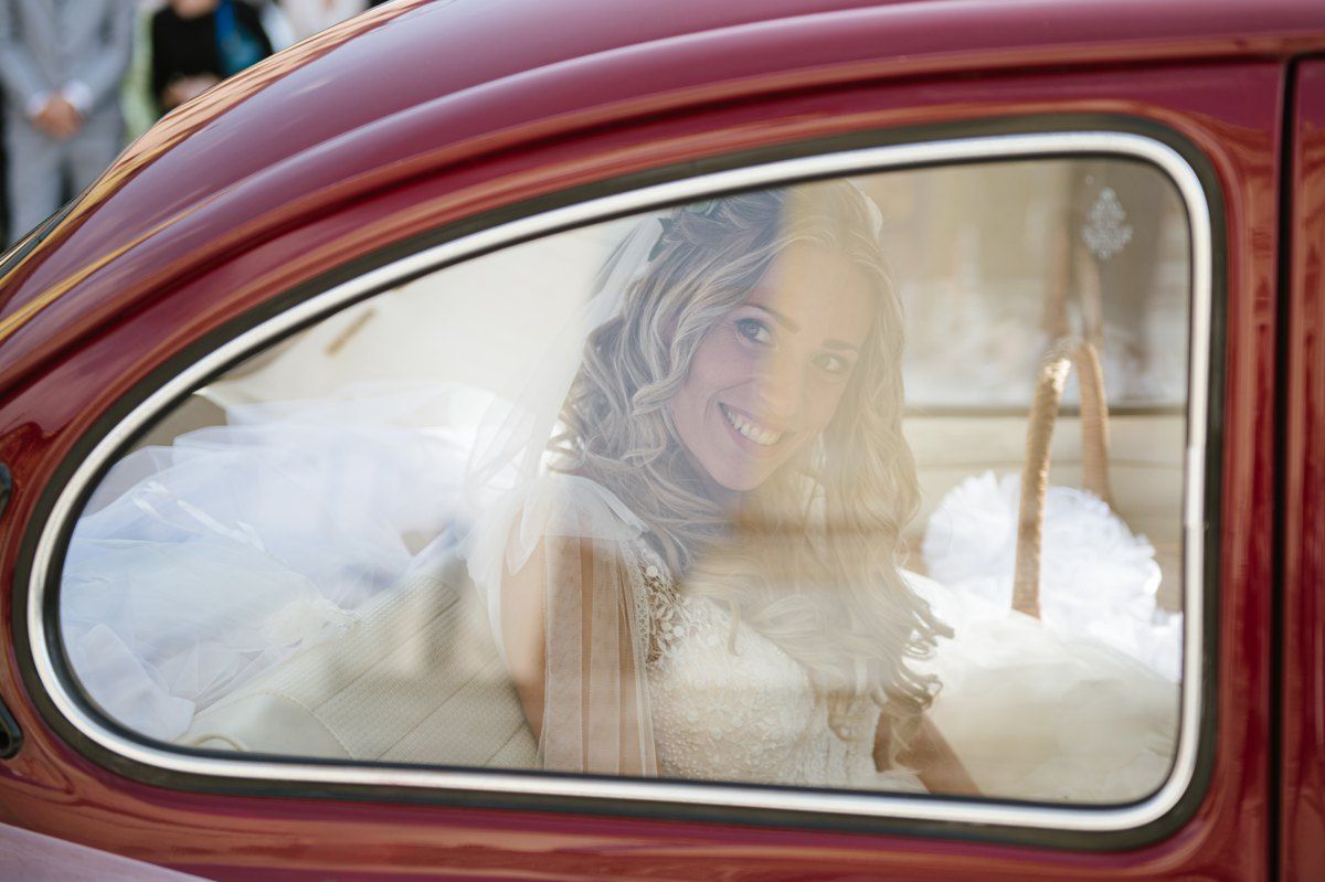 Vintage red car window framing view of special wedding moment.