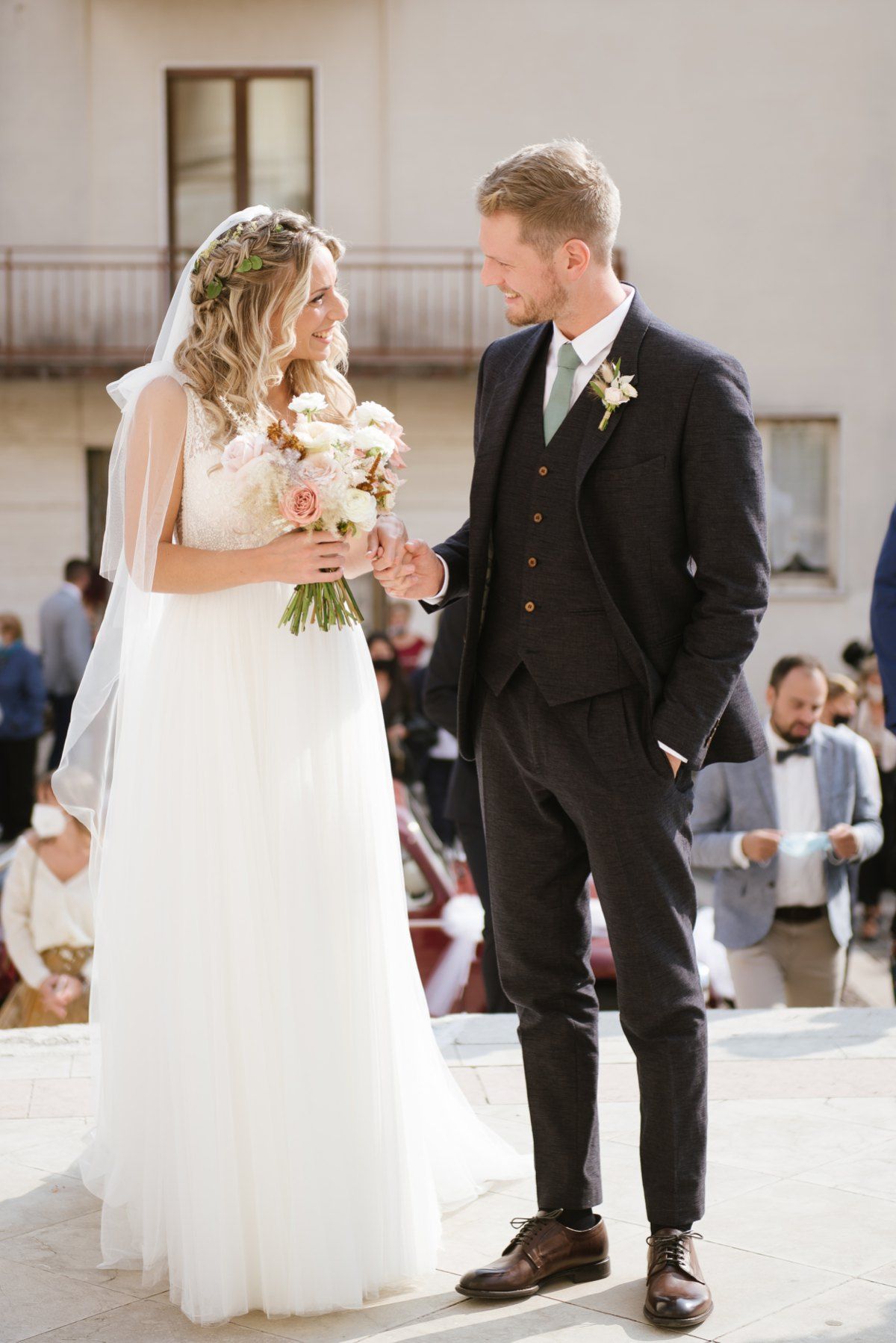 Wedding couple sharing a moment in elegant attire with floral bouquet.