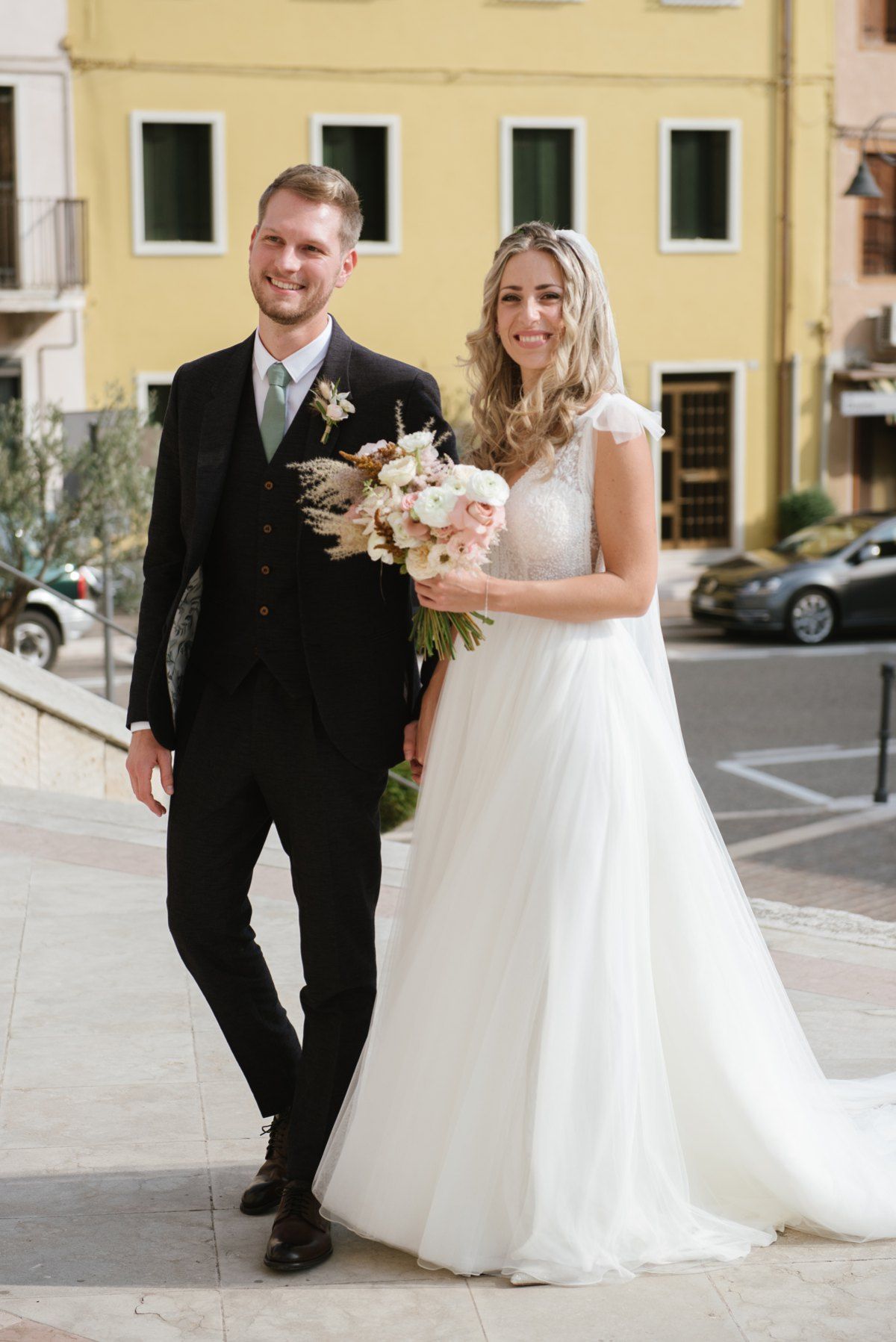 Newlyweds pose together on a charming Italian street with colorful buildings in the background.