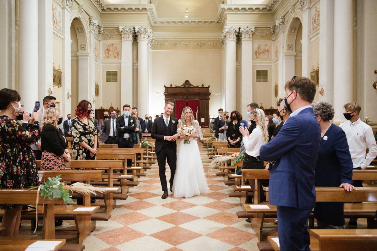 Inside a grand Italian church with ornate columns and checkered floors during a wedding ceremony.