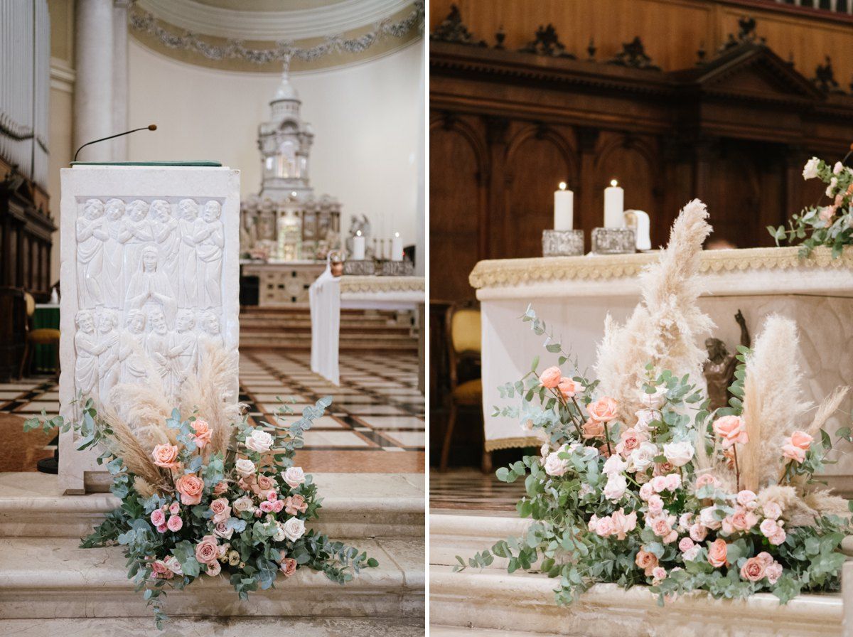 Beautiful floral arrangements with pink roses decorate a church altar during a wedding ceremony.