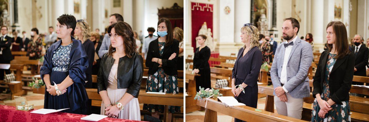 Wedding guests stand reverently inside an ornate church during a Catholic ceremony.